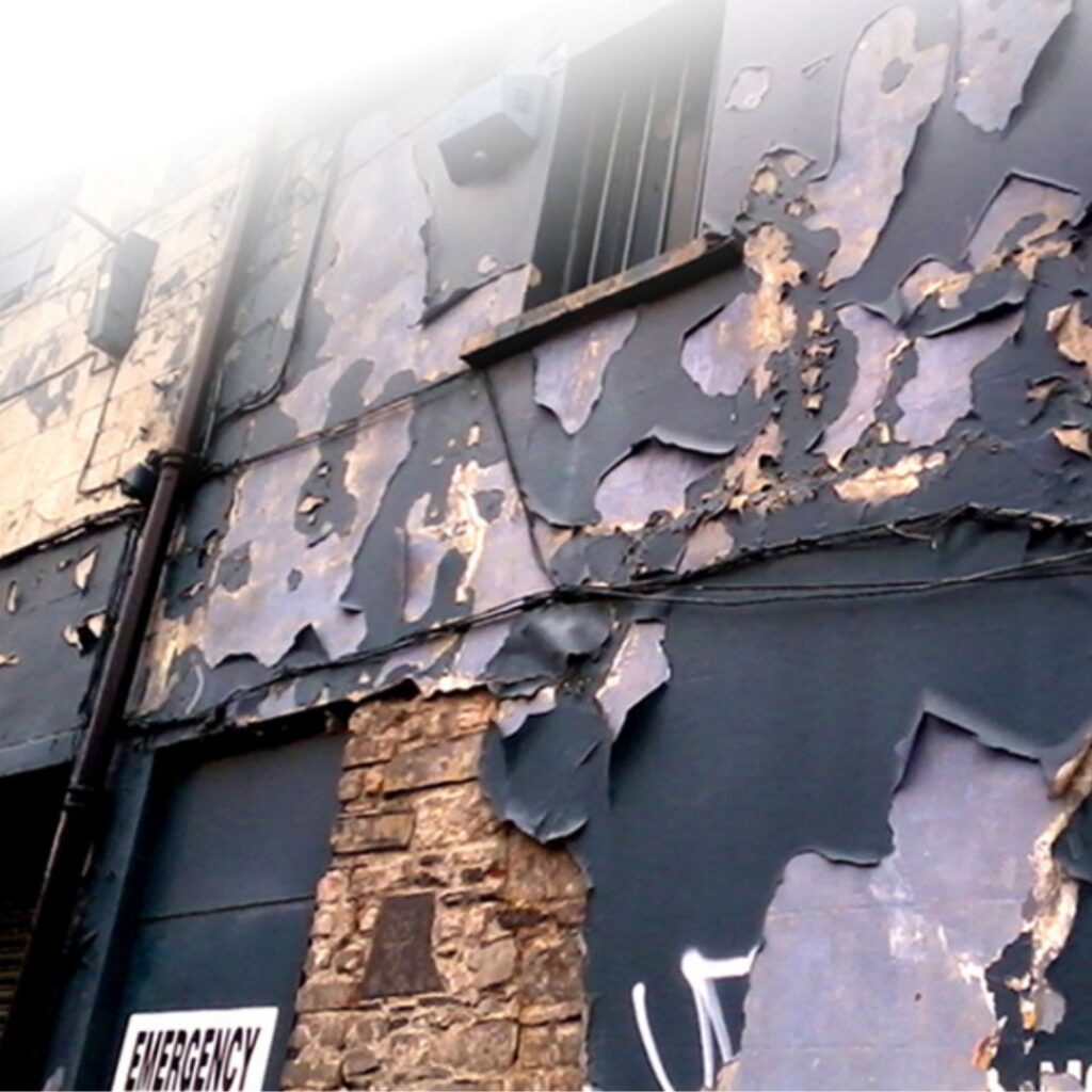 the grey wall with peeling paint and plaster