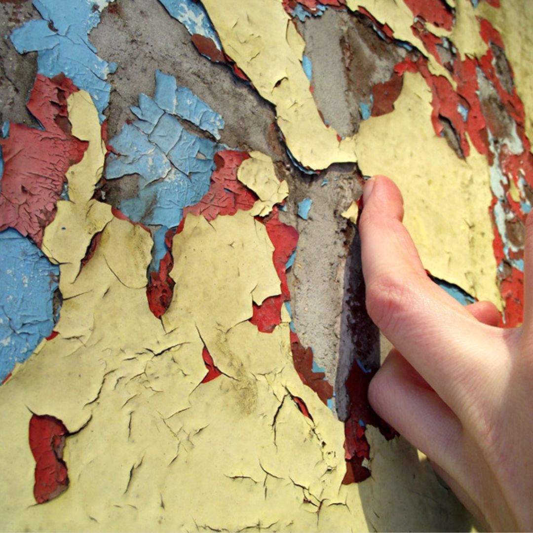 Hand scraping peeling paint from a Dublin wall